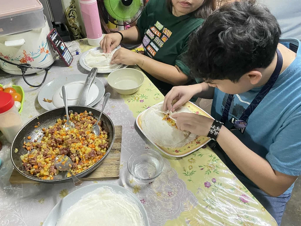Preparing lumpia together at the foster family’s kitchen table.