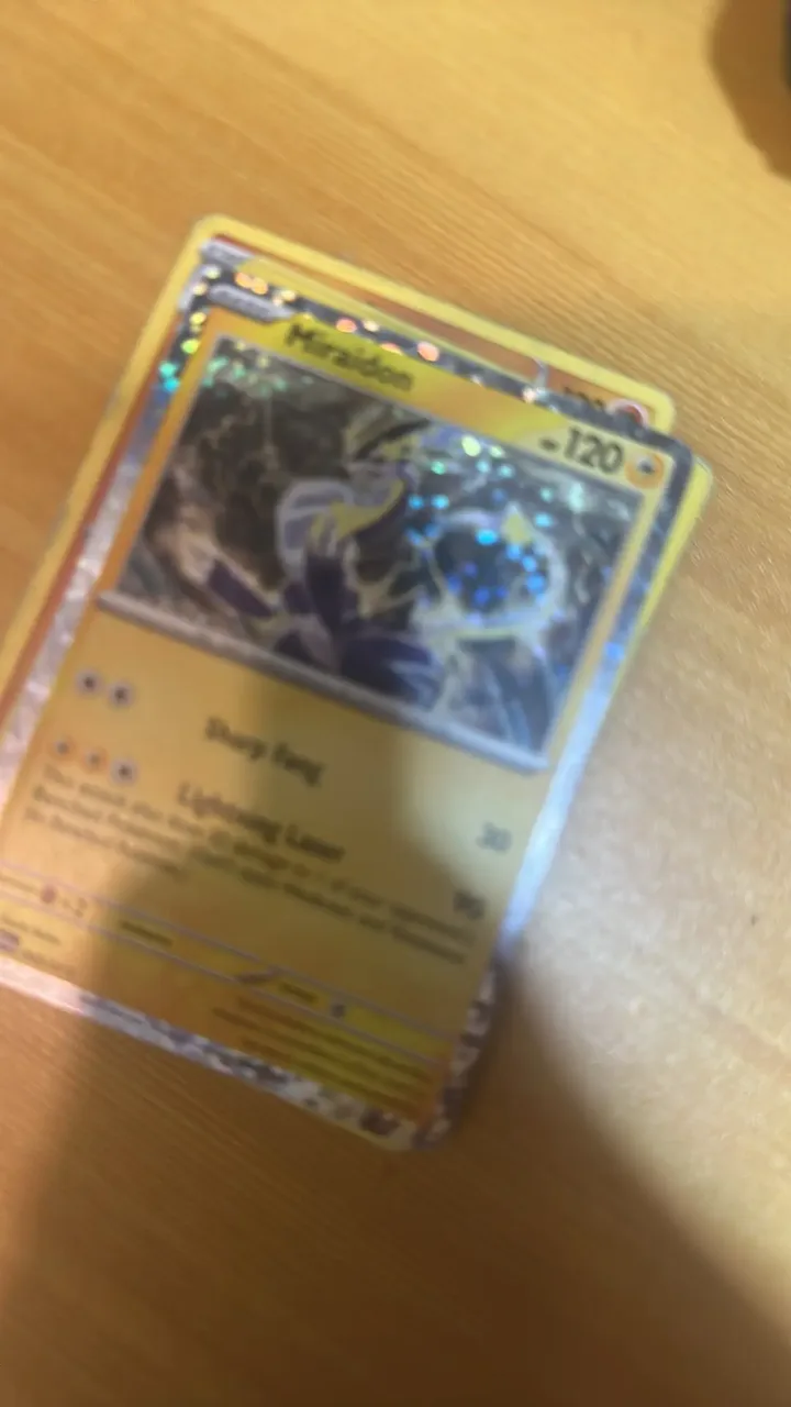 A holographic Miraidon Pokémon card on a wooden table.