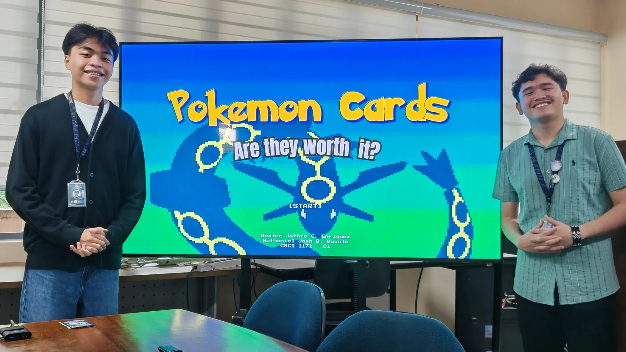 DJ and Nat standing on either side of a large screen showing the title slide, Pokemon Cards: Are they worth it?
